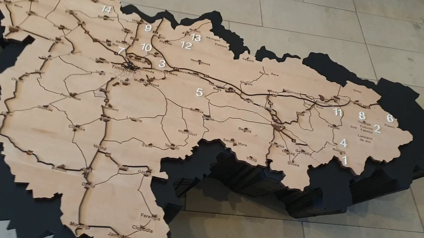 A large wooden relief map of a county with numbered sights, roads and town names, on a black stand