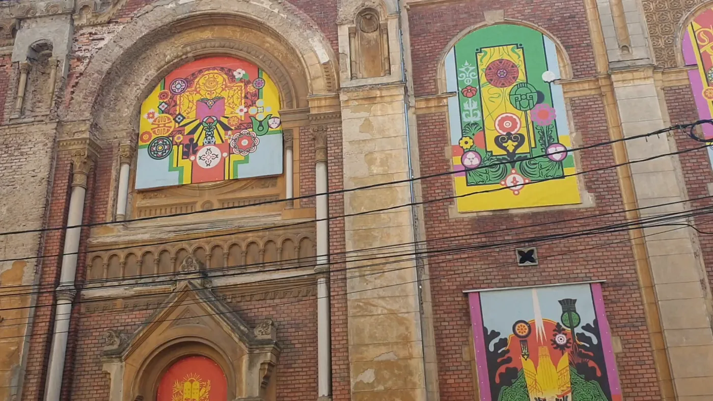 Close view of arched brick window openings filled with bright red, yellow, green and pink painted panels