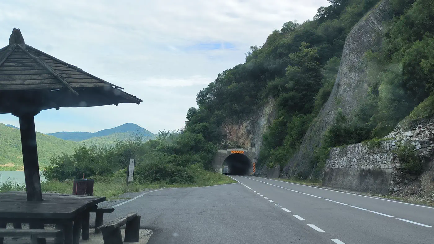 The gorge road east of Golubac in Serbia with a tunnel through the rock and a wooden picnic shelter beside the Danube